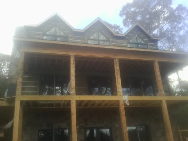 Dormers and porch framing on a large log home under construction — Roof Coating work by our crew in Sprague