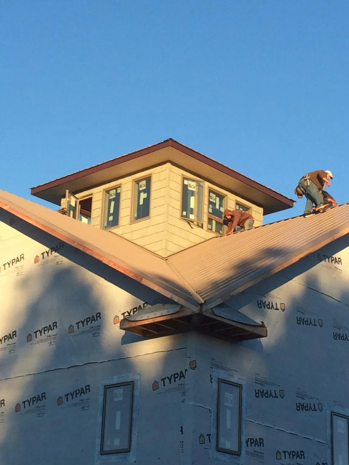 Roofers working around a rooftop cupola on a new metal roof at sunset — Roof Waterproofing in Sprague by Roofing Brothers